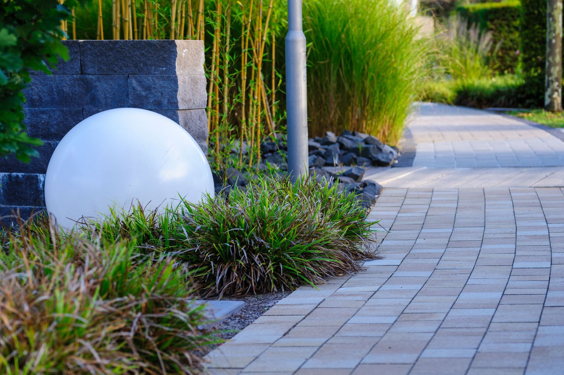A tranquil garden pathway featuring a modern white sphere and lush greenery.