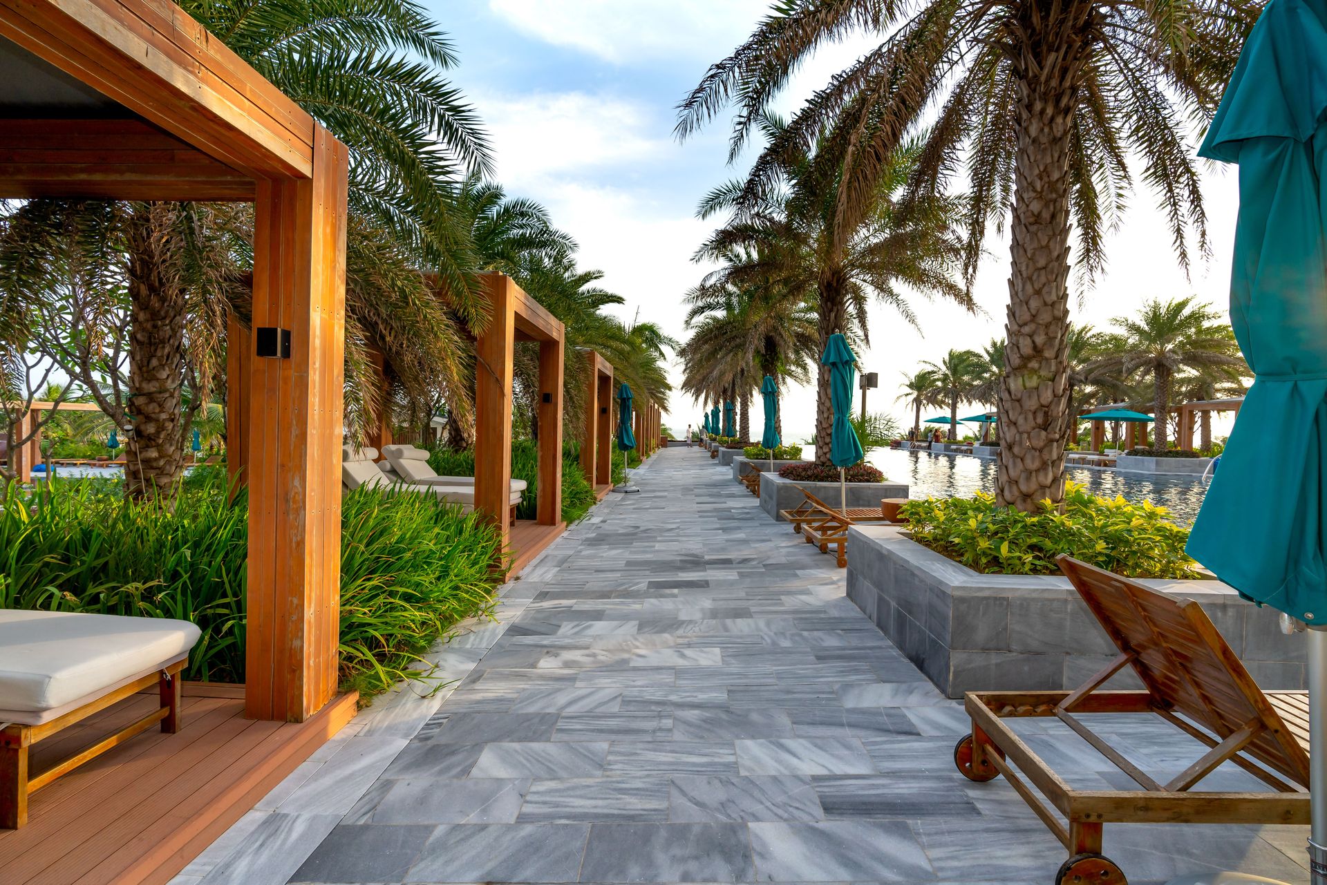 Stunning resort walkway lined with palm trees and relaxation spots by a poolside.
